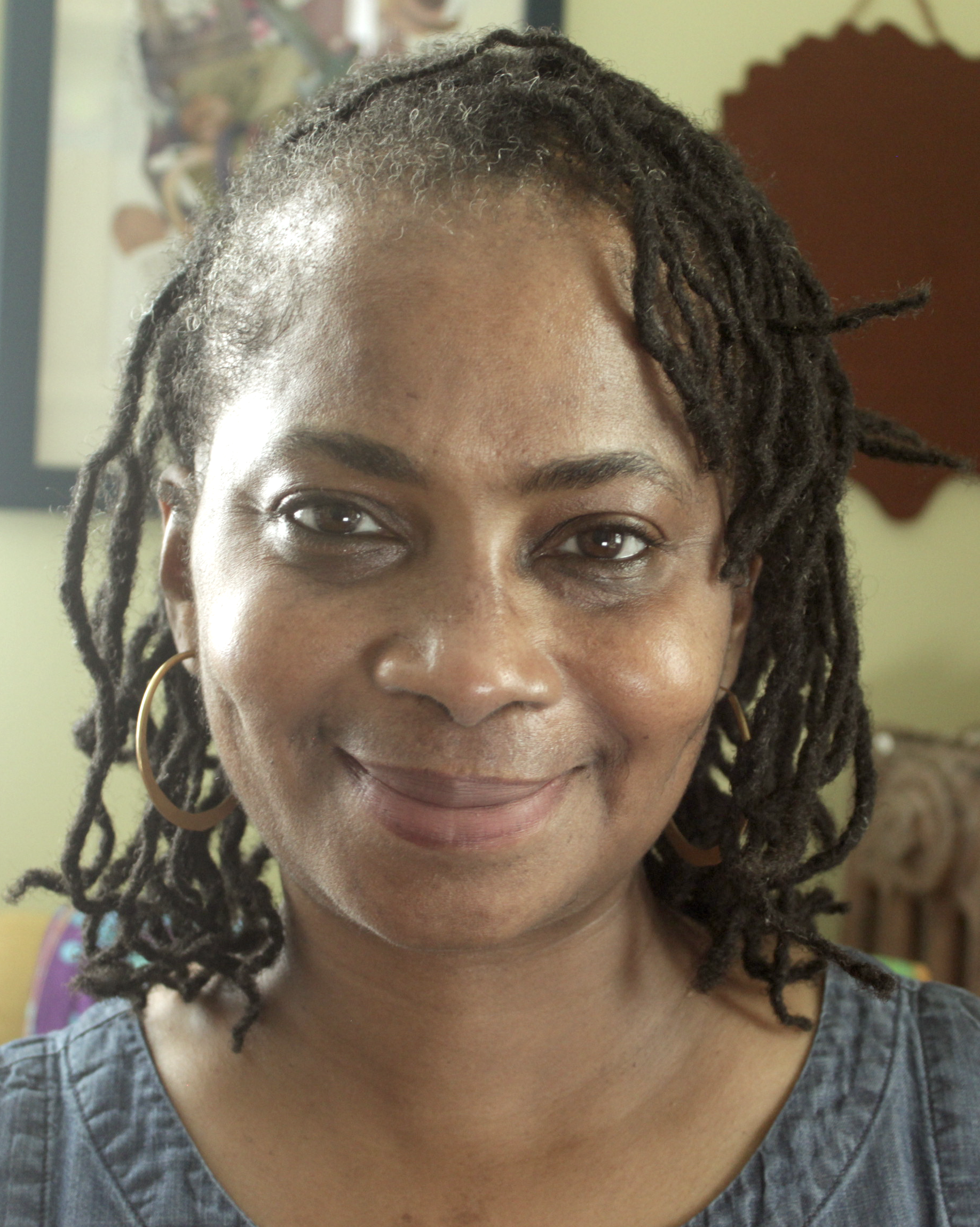Smiling woman wearing a yellow patterned headband and hoop earrings.